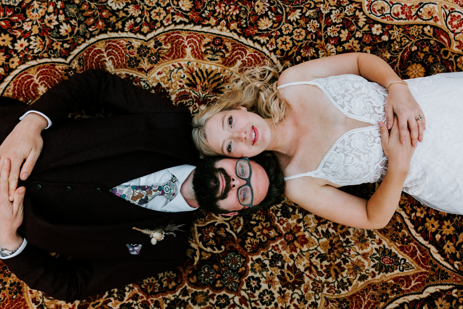 professional wedding photography of a couple lying on rug 